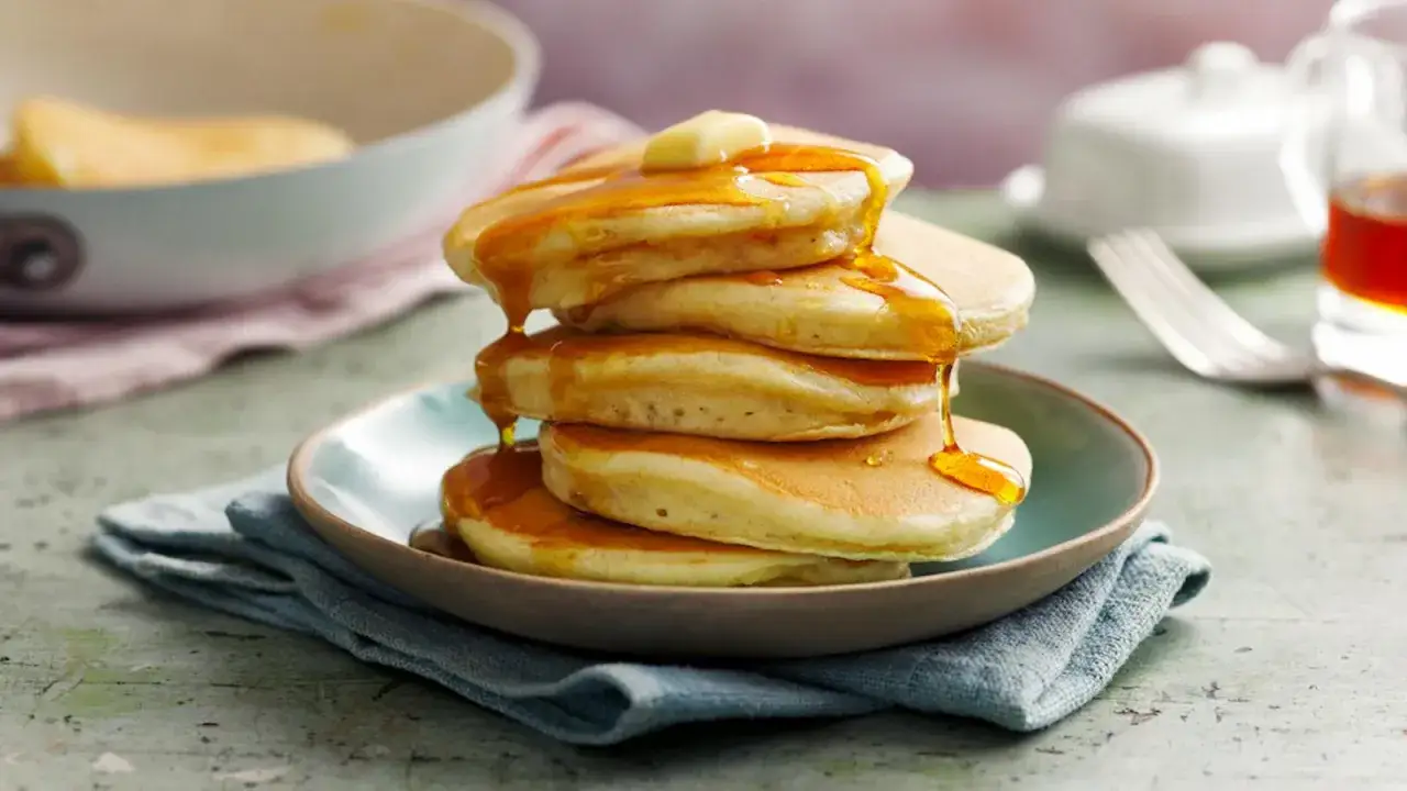 Pile de pancakes dorés, nappés de sirop d'érable et d'une noix de beurre. Une invitation à découvrir la recette parfaite pour un petit-déjeuner gourmand.