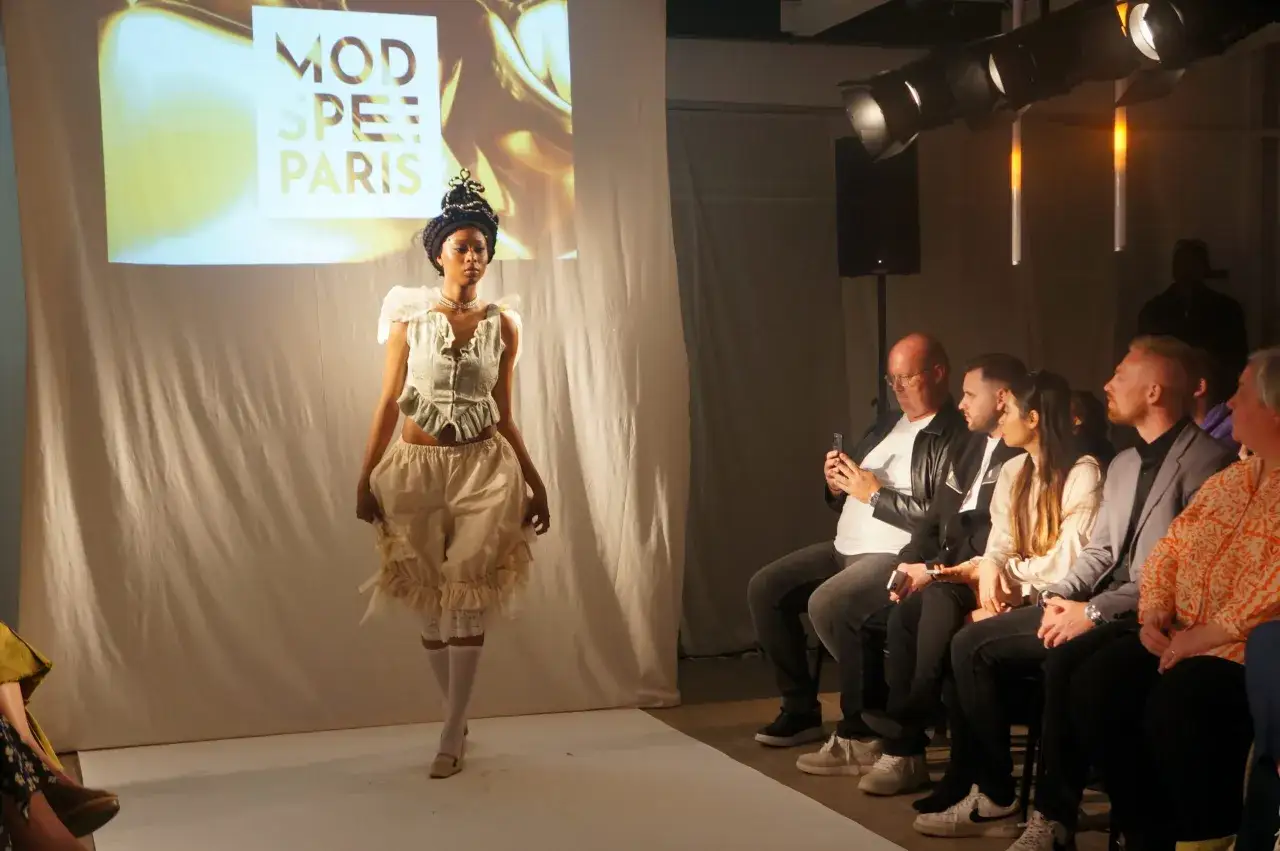 D&eacute;fil&eacute; de mode : une jeune femme pr&eacute;sente une tenue originale sur fond d'&eacute;cran 