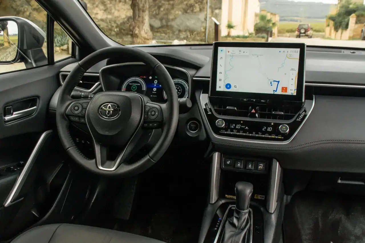 Wnętrze nowego modelu Corolla Cross 2025 z ekranem nawigacji i kierownicą.