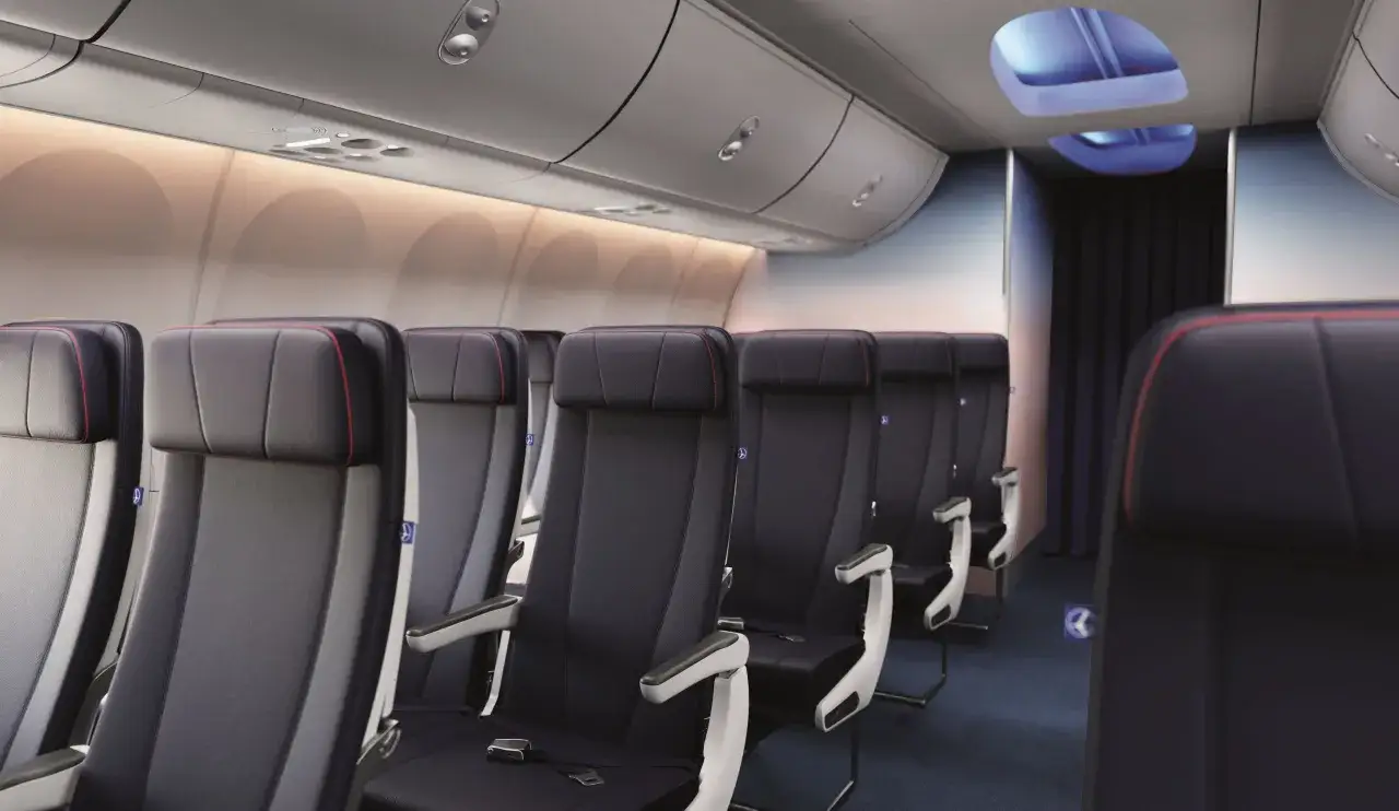 Wnętrze samolotu Boeing 737 MAX 8 z rzędami ciemnych foteli, oświetlone ciepłym blaskiem.