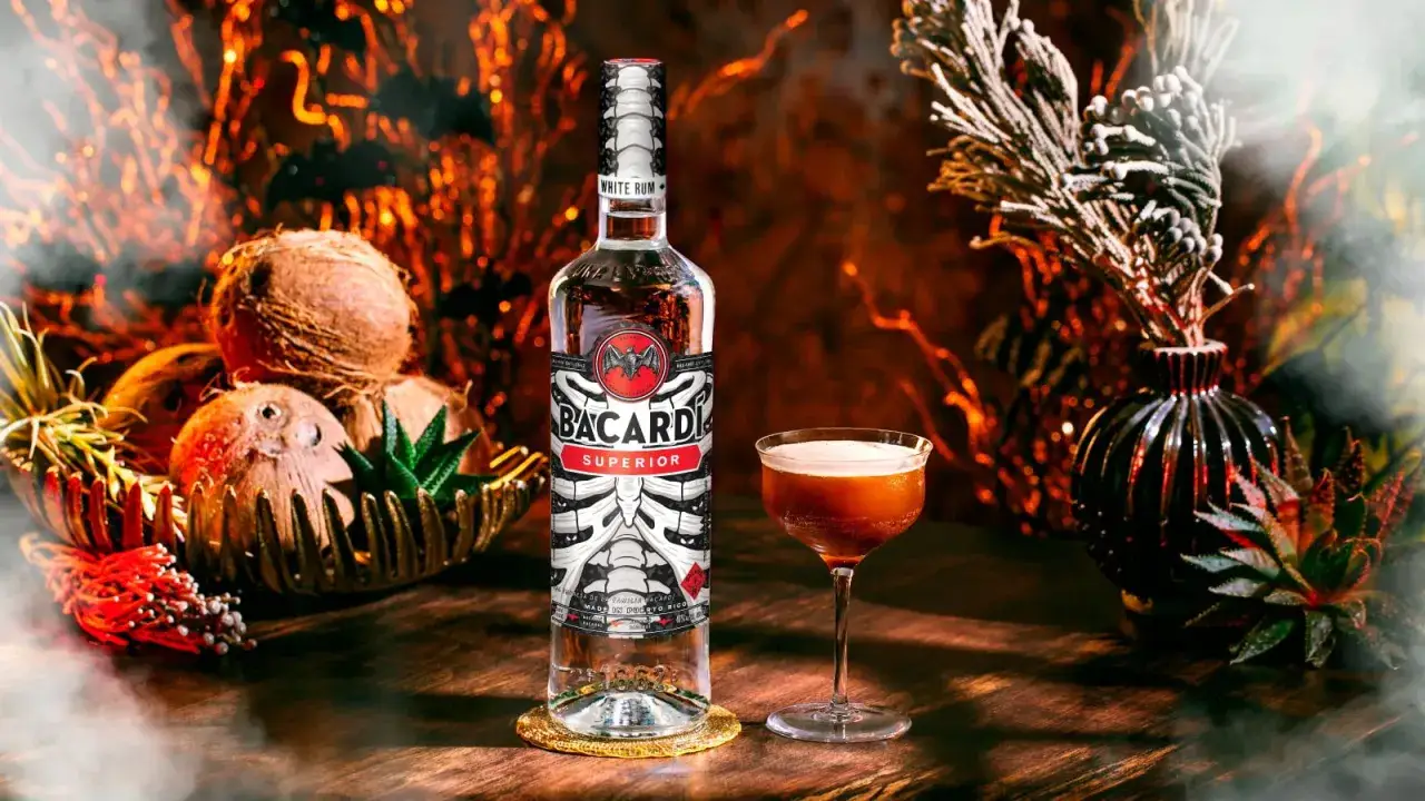 Bacardi Superior - biały rum, idealny do koktajli. Na stole butelka, drink i kokosy.