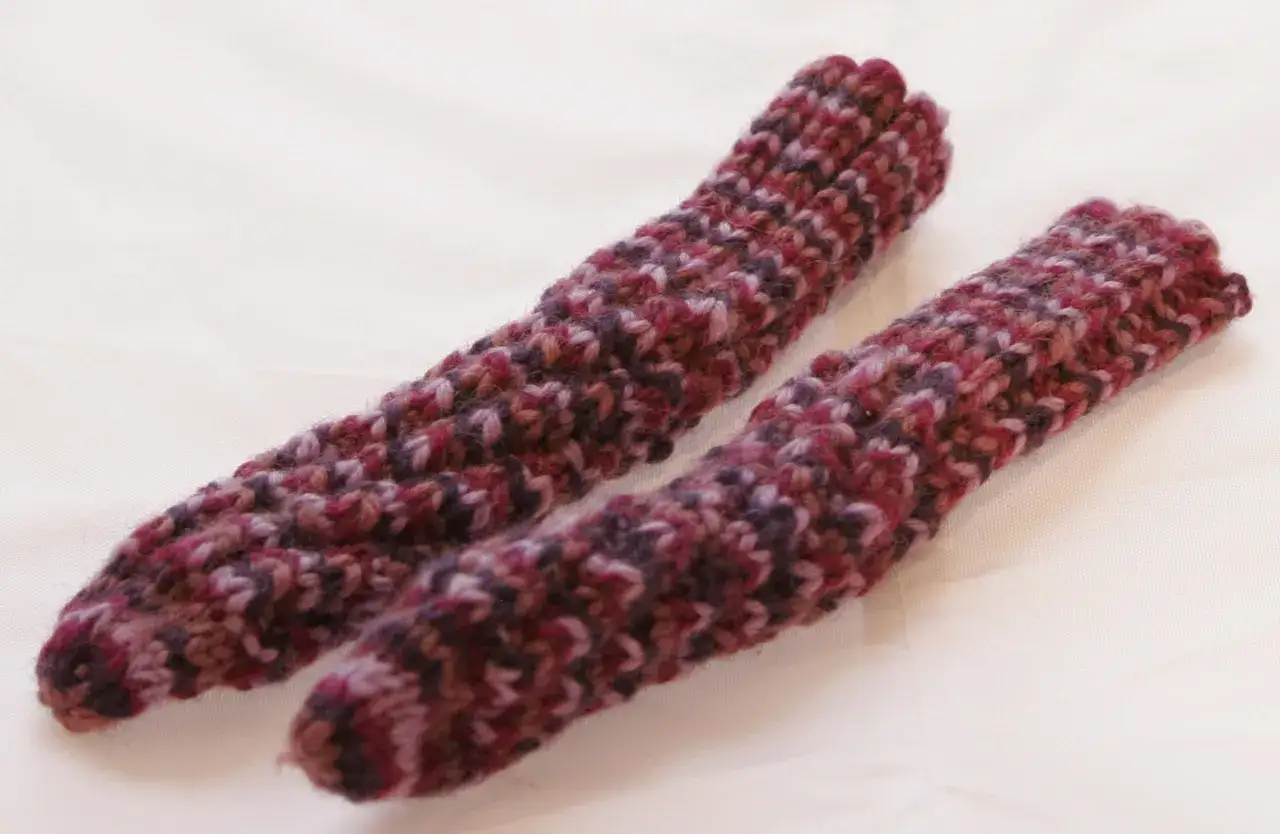 Tv&aring; handstickade drops spiralsockor i ett flerf&auml;rgat garn med lila och vinr&ouml;da toner.