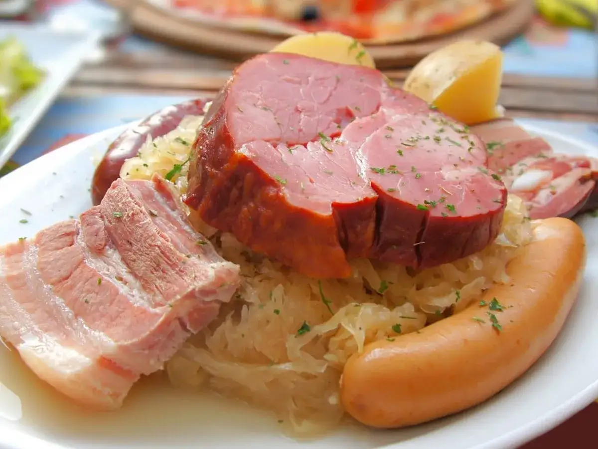 Assiette de spécialités culinaires alsaciennes : choucroute garnie avec lard, saucisses et jambon fumé.