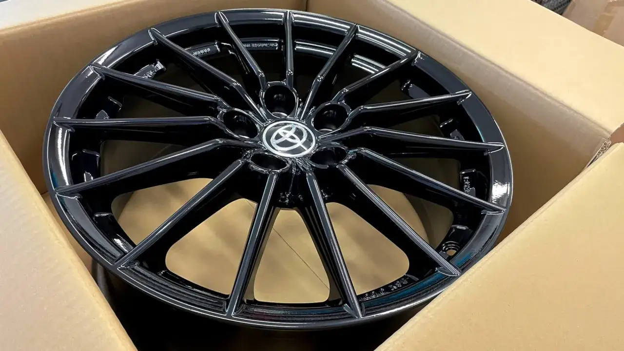 Błyszcząca, czarna felga do Toyota Yaris Sport z logo producenta w centrum, gotowa do montażu.
