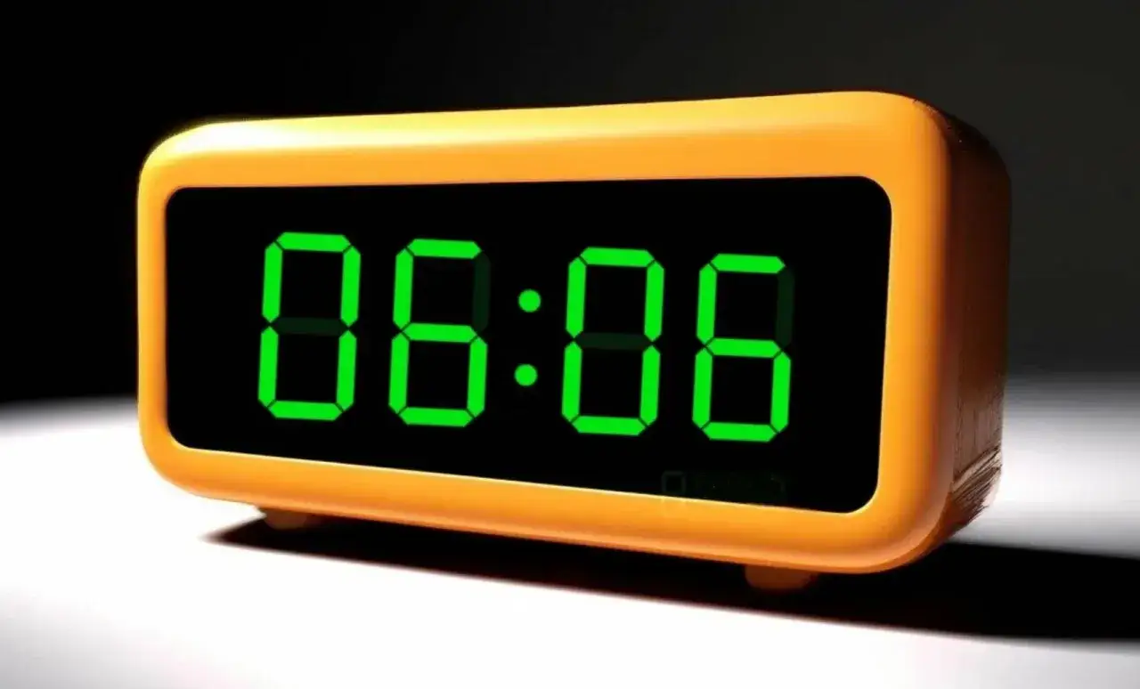 Pomarańczowy budzik pokazuje godzinę 06:06. Czas na pobudkę!