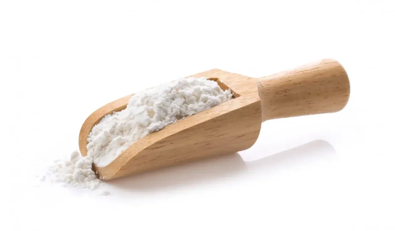 Une cuillère en bois remplie de farine blanche, parfaite pour savoir par quoi remplacer la farine de seigle dans vos recettes.