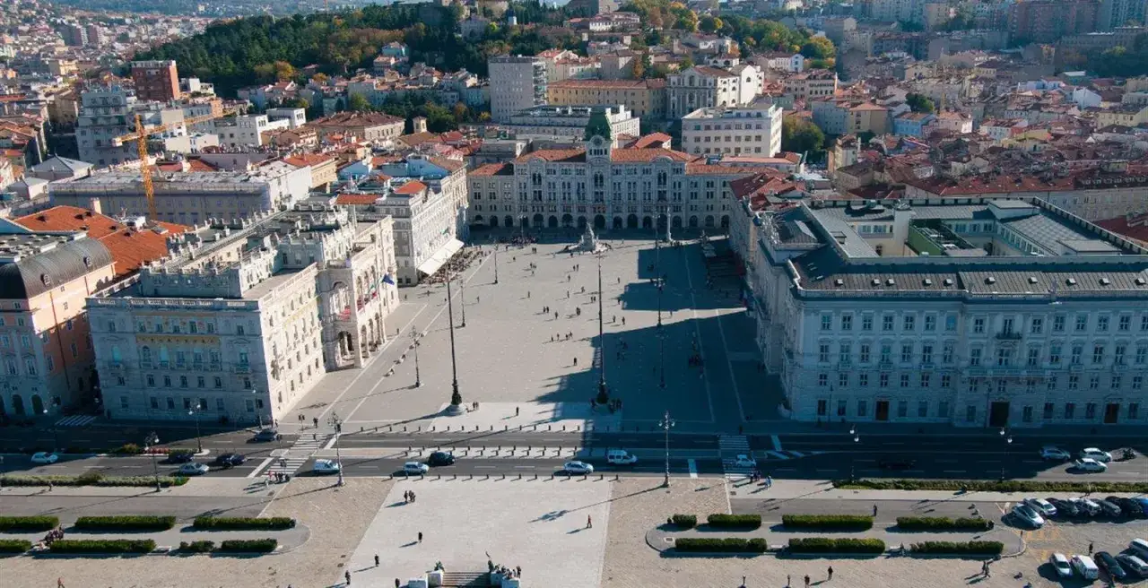Ampia vista aerea di **Piazza Unità d'Italia** a Trieste, con i suoi palazzi storici e il mare sullo sfondo.