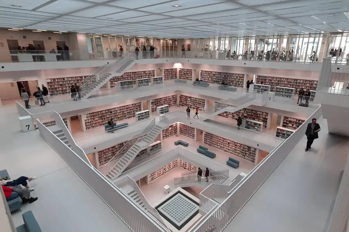 Moderne Bibliothek mit offenen Galerien, Treppen und Regalen voller Bücher. Ein Beispiel für beste Architektur Uni Deutschland.