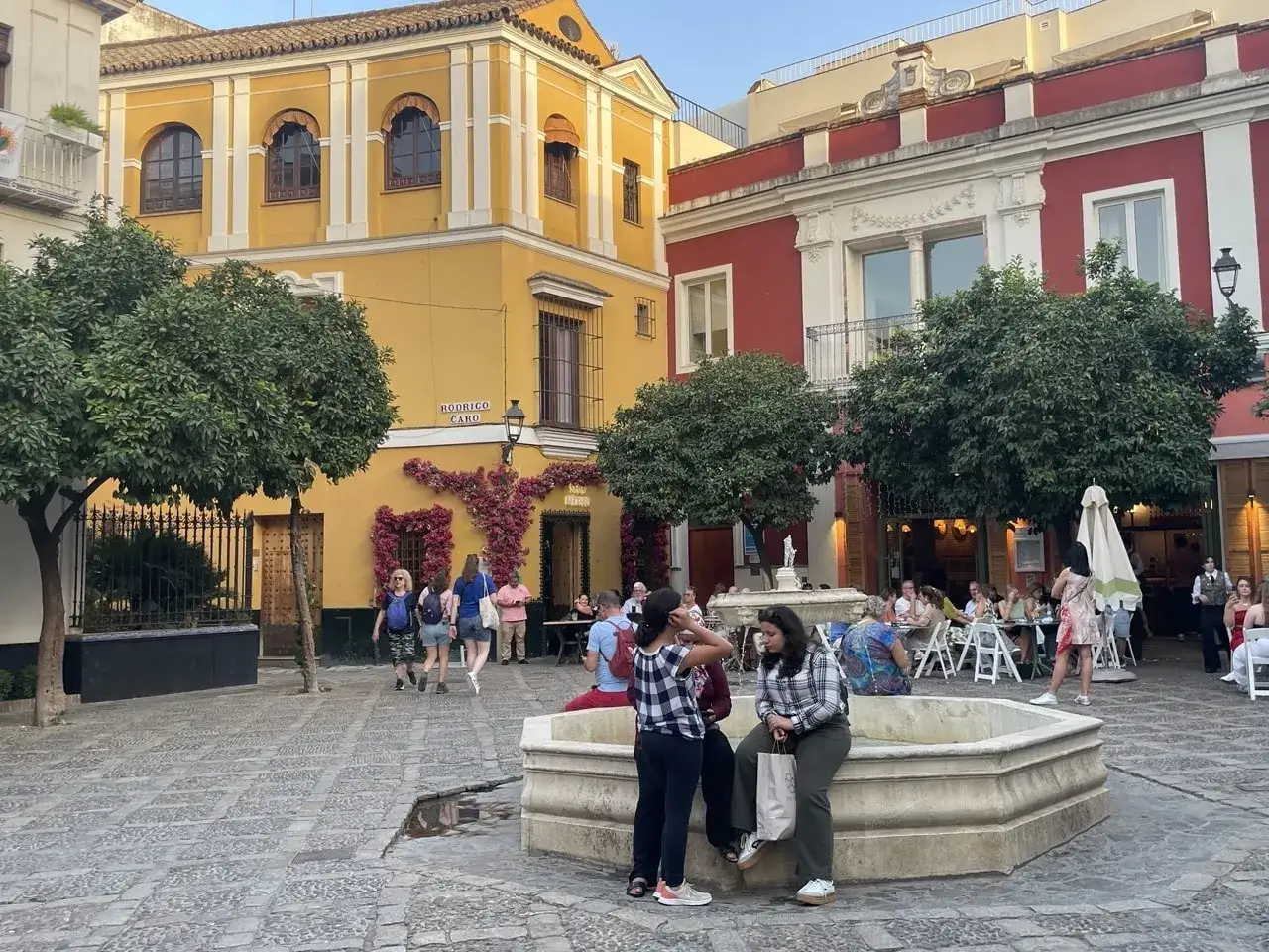 En livlig torg i Sevilla, Spanien, med folk som sitter vid bord utomhus och njuter av kv&auml;llen.