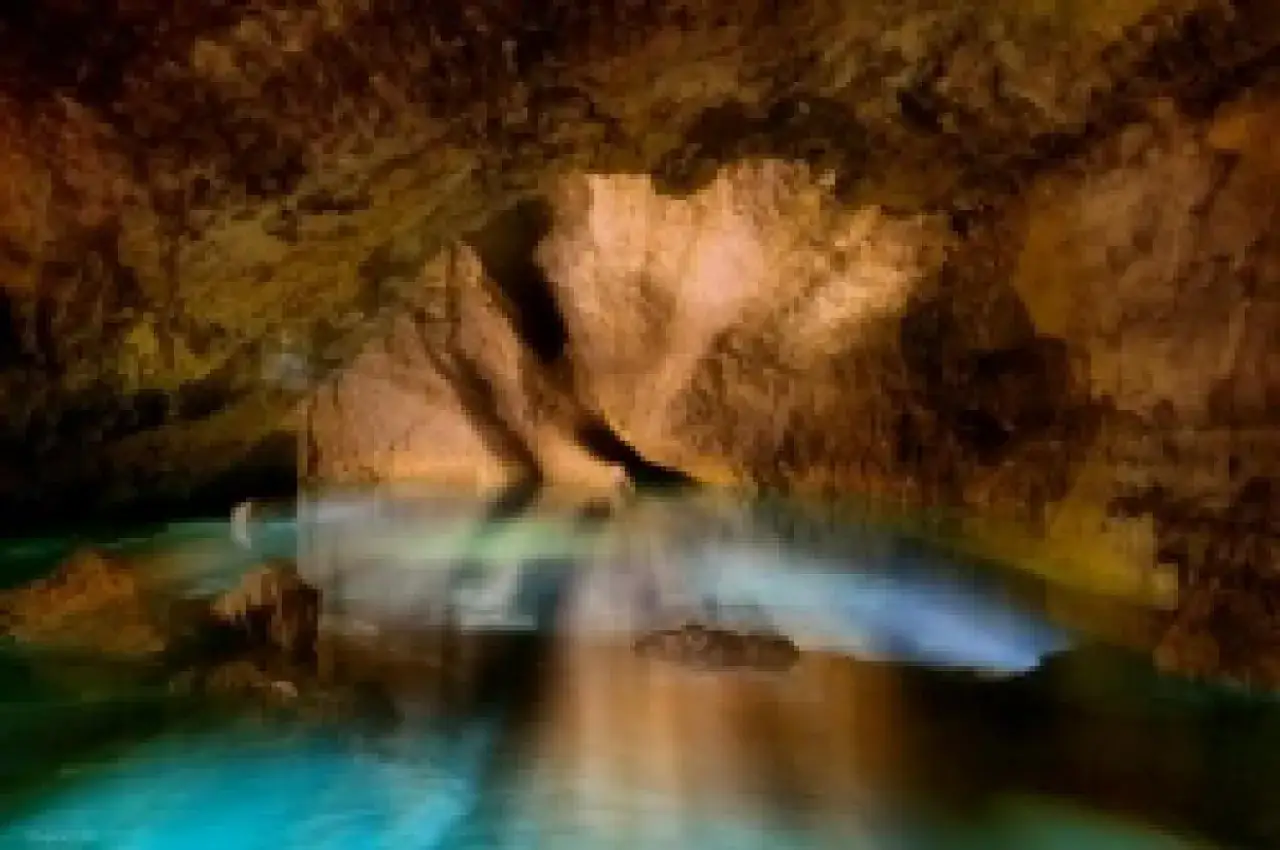 Podziemne jezioro w **Boźkowskich jaskiniach dolomitowych**. Woda lśniąca turkusem odbija skalne nacieki.