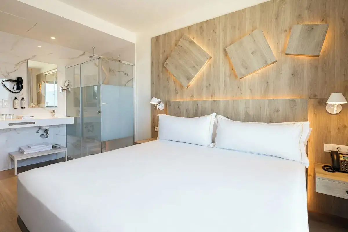 Habitación moderna con cama doble, baño de cristal y detalles de madera. Un lugar perfecto para el senador Gandía.