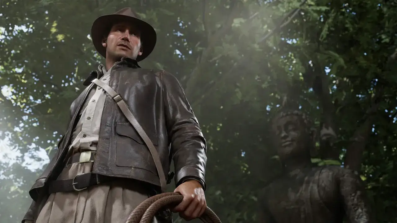 Indiana Jones i Wielki Krąg: archeolog w skórzanej kurtce i kapeluszu, z biczem w dłoni, stoi przed kamiennym posągiem w gęstym lesie.