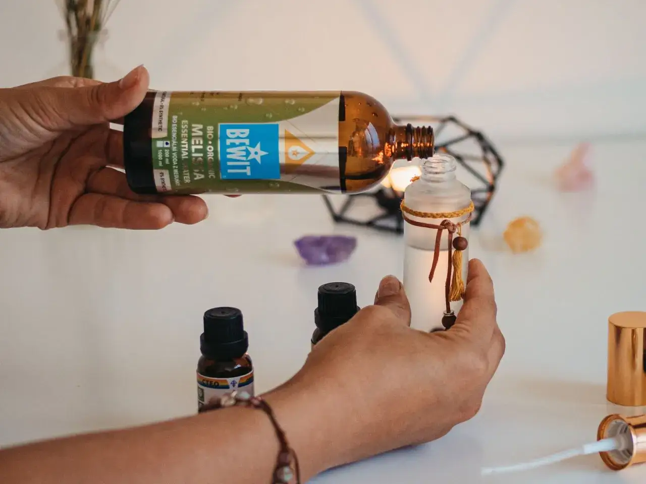 H&auml;nde f&uuml;llen ein Fl&auml;schchen mit Melissenhydrolat. Die beruhigende Melissenhydrolat Wirkung wird f&uuml;r Entspannung genutzt.