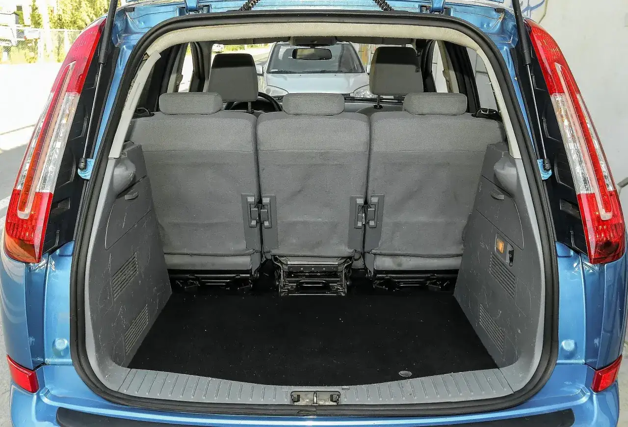 Błękitny Ford C-Max z otwartym bagażnikiem. Widok na tylne siedzenia i pustą przestrzeń bagażową. Idealny do przewozu bagażu, co potwierdzają liczne ford c max opinie.
