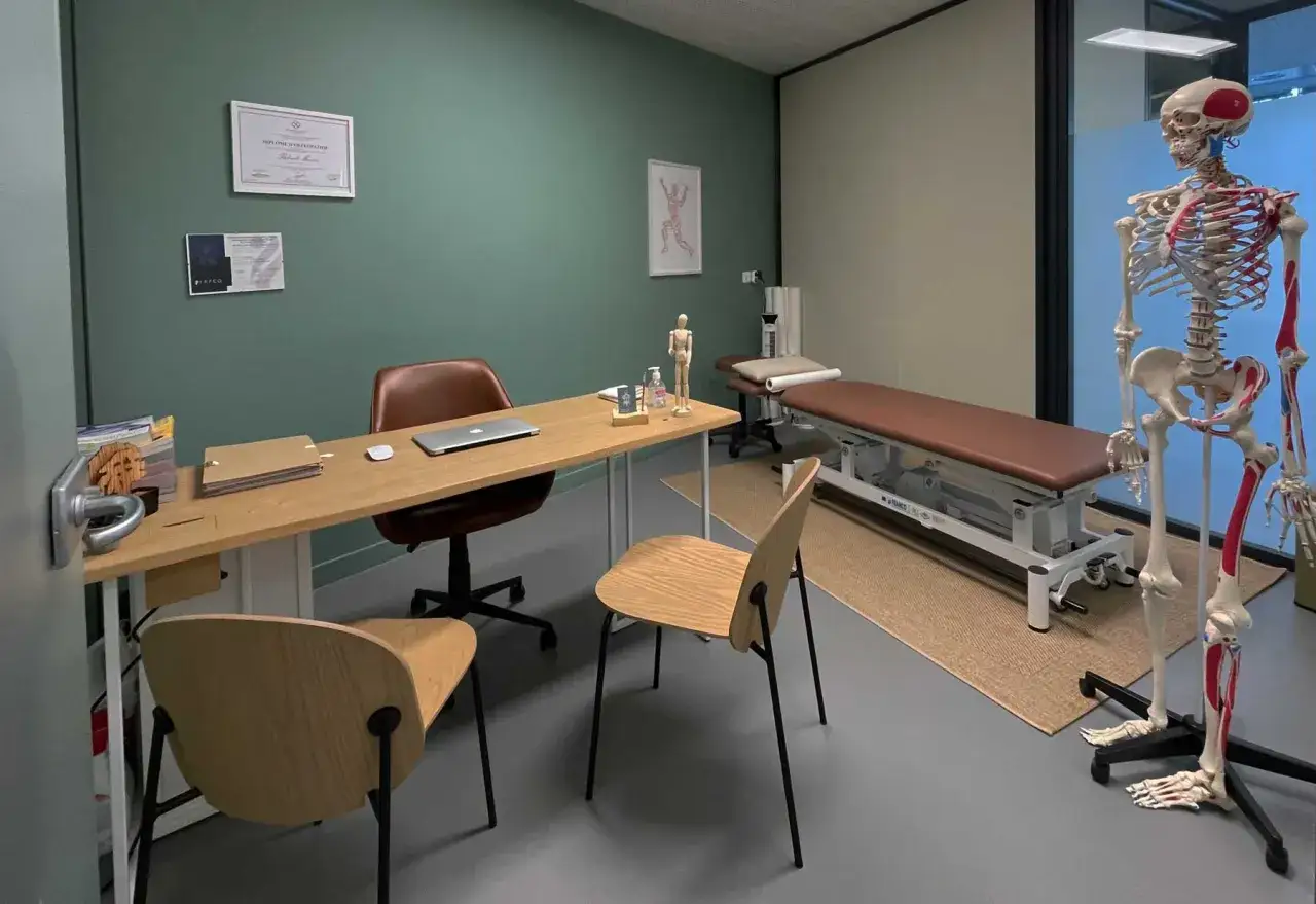 Bureau d'ostéopathe avec un squelette anatomique, une table de massage et des diplômes. Idéal pour un massage ostéopathe.