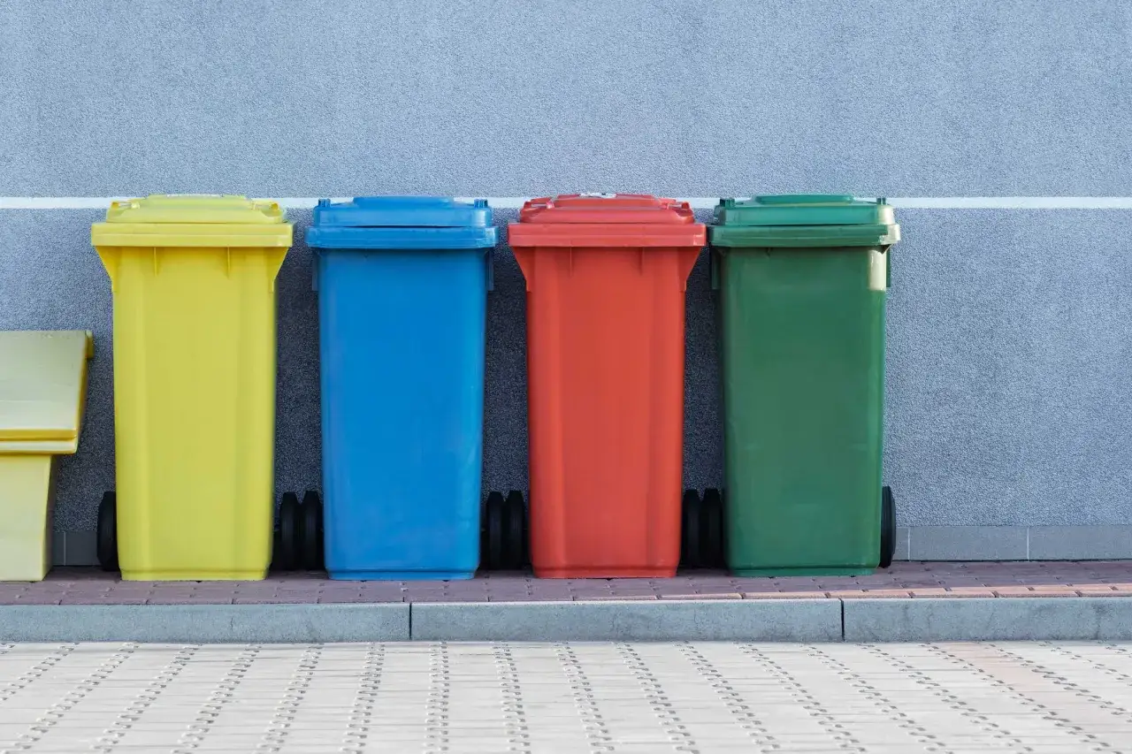 Cztery kolorowe kosze na śmieci: żółty, niebieski, czerwony i zielony, stoją obok siebie. Mogą służyć do segregacji odpadów, w tym odpadów medycznych.