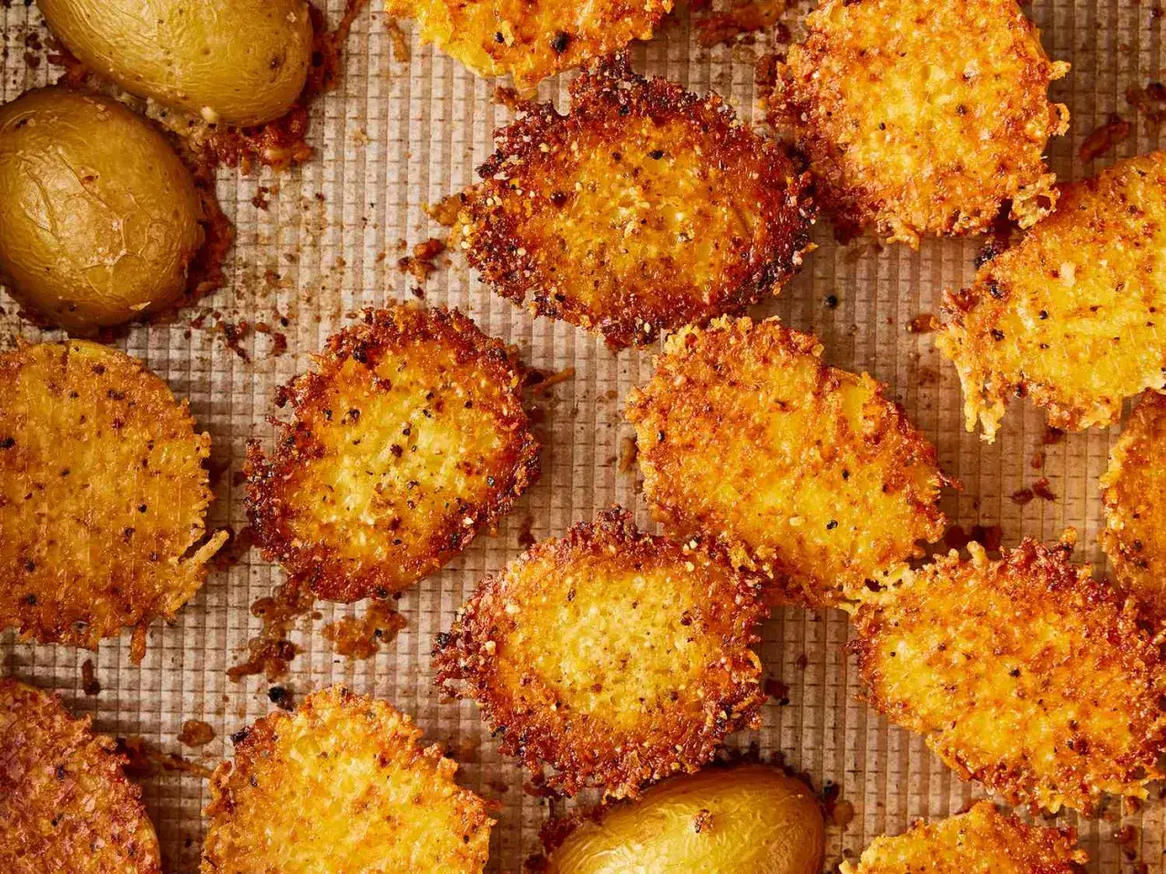 Des rondelles de pommes de terre dor&eacute;es et croustillantes, enrob&eacute;es d'une d&eacute;licieuse cro&ucirc;te parmesan comestible, sur une plaque de cuisson.