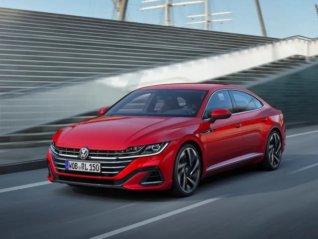 Czerwony Volkswagen Arteon R sunie po drodze, jego sportowy design przyciąga wzrok.