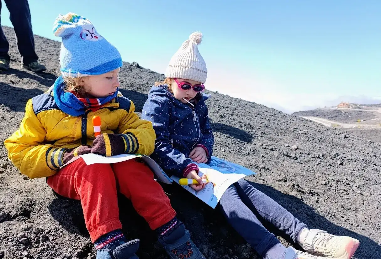 Bambini vestiti a strati, con cappelli e giacche calde, imparano come vestirsi per andare sull'Etna.