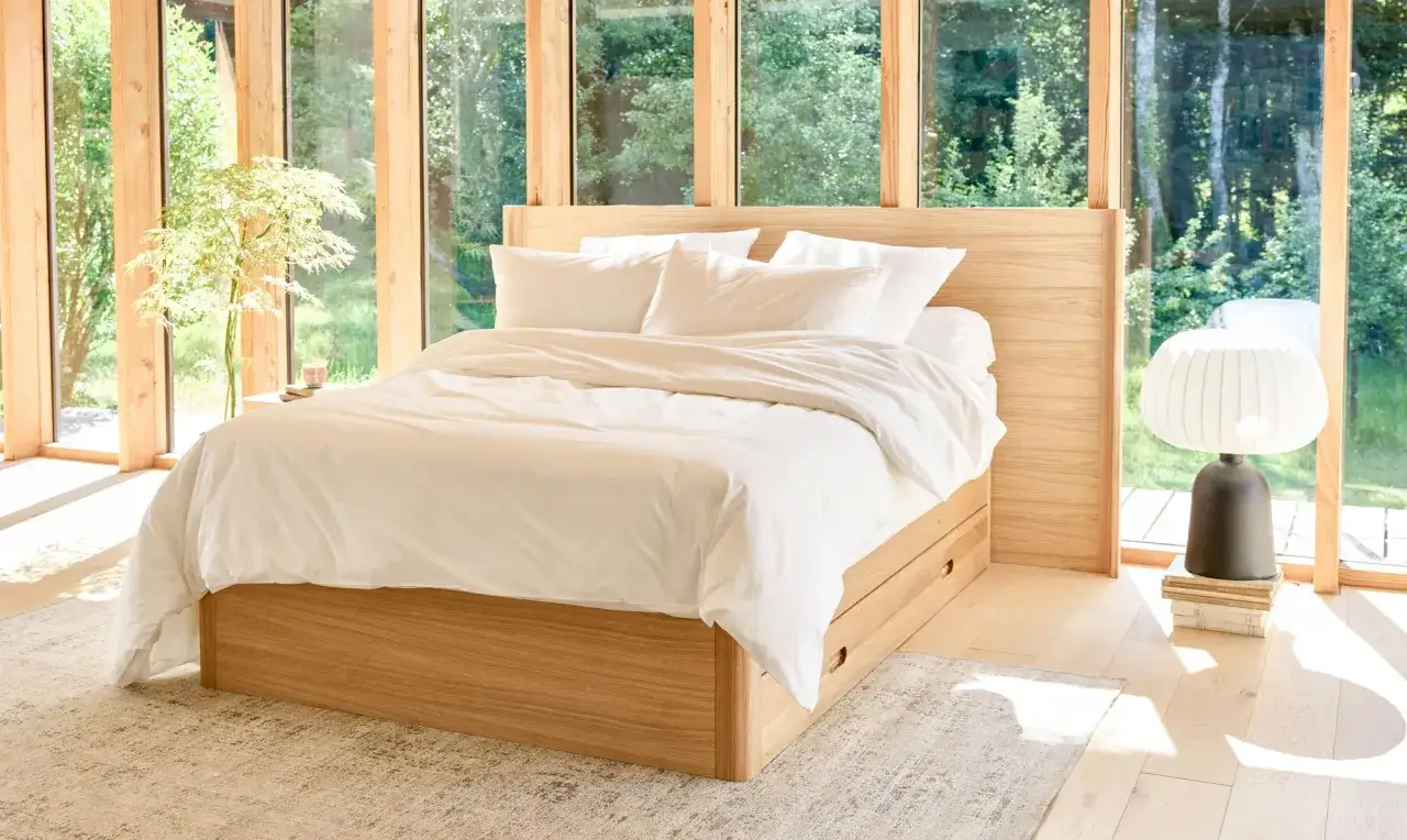 Lit en bois clair, draps blancs immaculés, ambiance zen pour une rénovation chambre réussie. Lumière naturelle abondante.