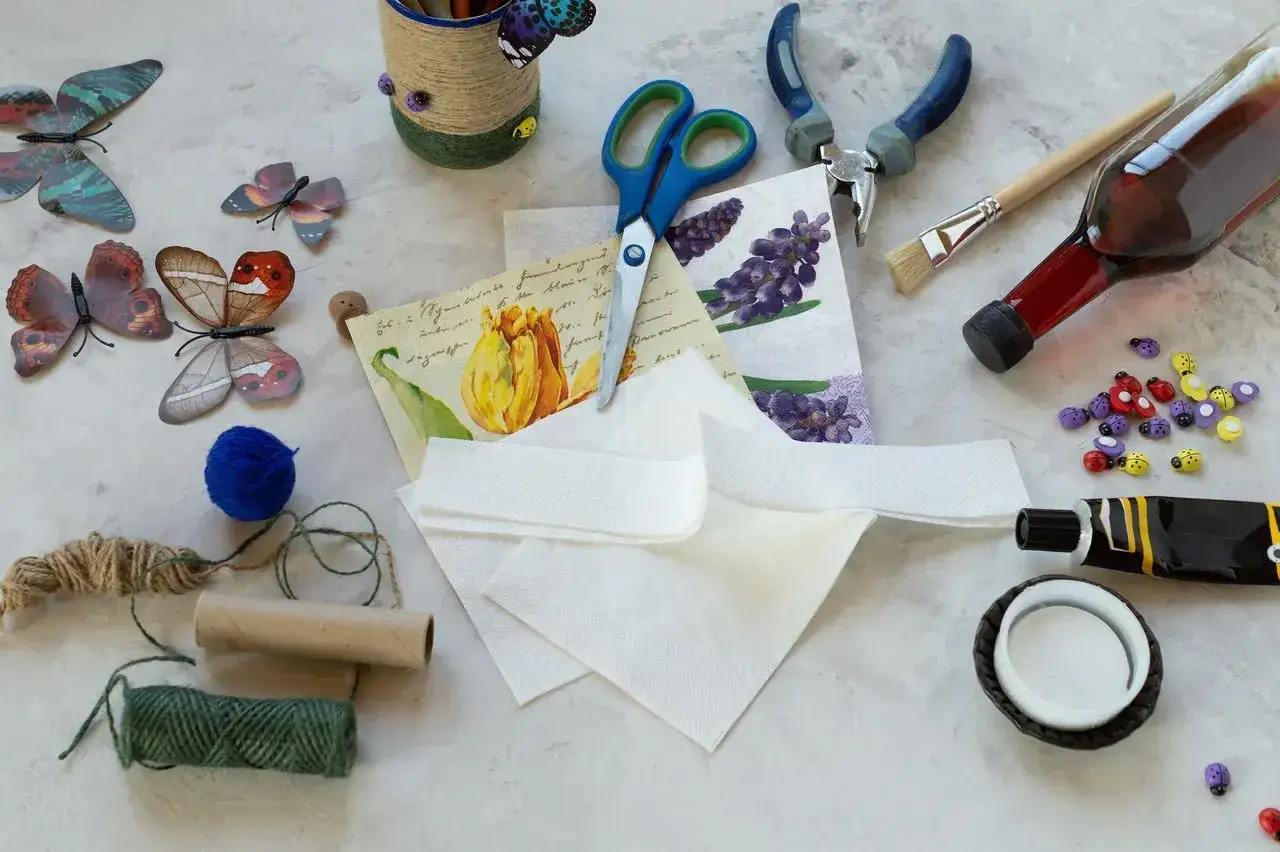 Materiały do decoupage krok po kroku: motyle, serwetki, klej, nożyczki, pędzel, butelka z płynem.