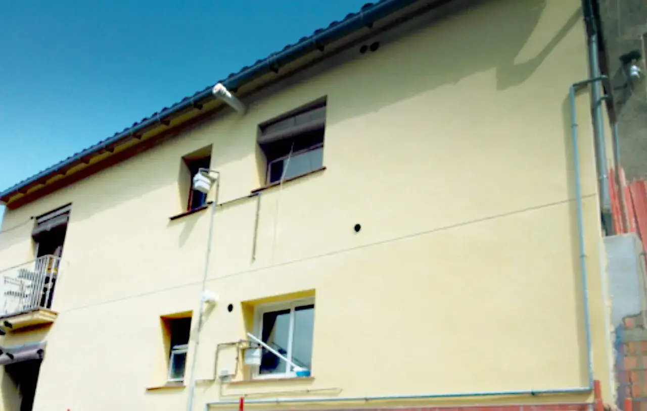 Fachada de edificio con ventanas y tuber&iacute;as. El sol brilla, como si quisiera revocar el fr&iacute;o del invierno.
