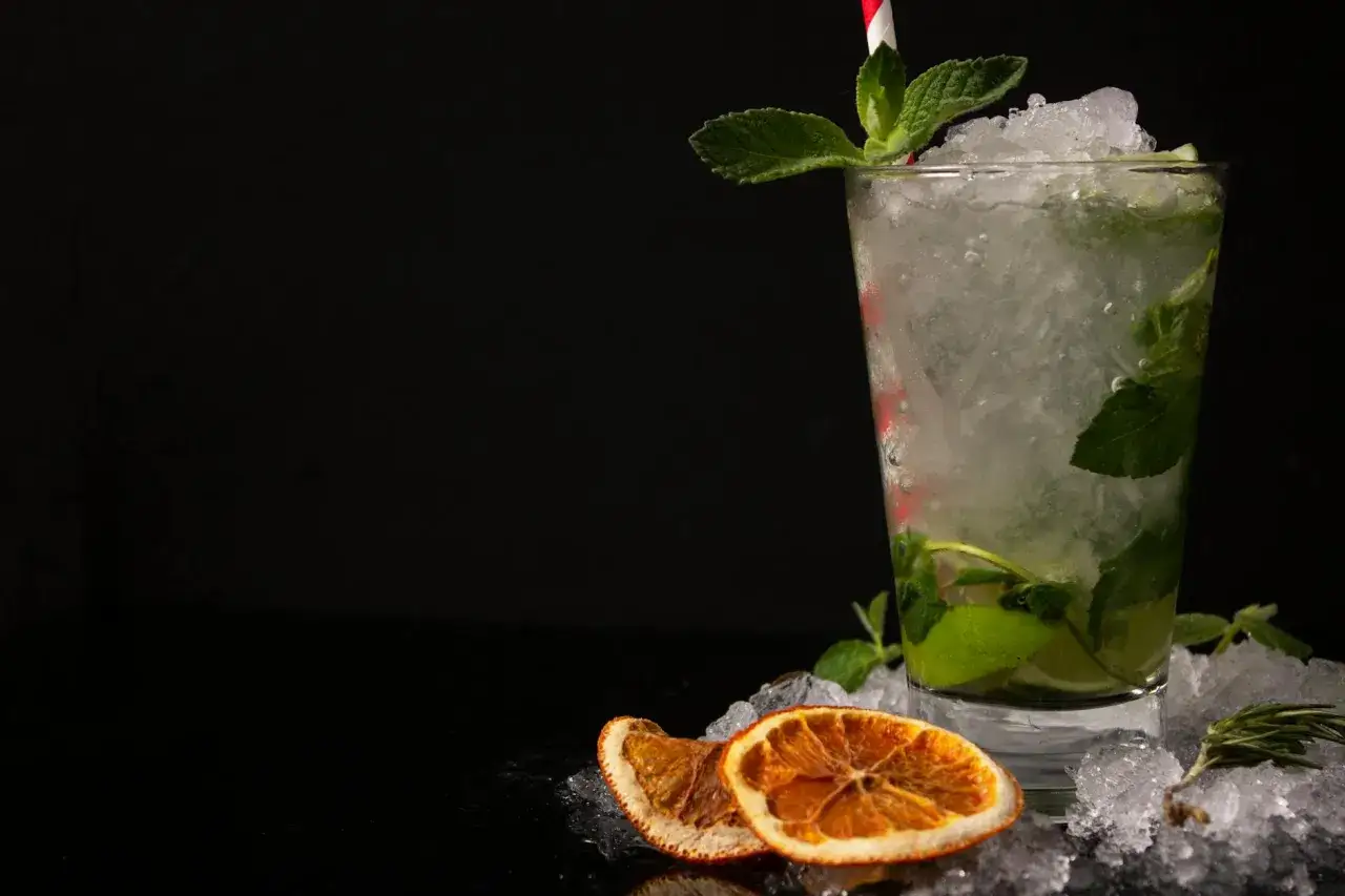 En uppfriskande mojito med mynta och lime, perfekt för ett somrigt mojito recept. Iskross, torkad apelsin och rosmarin fulländar presentationen.