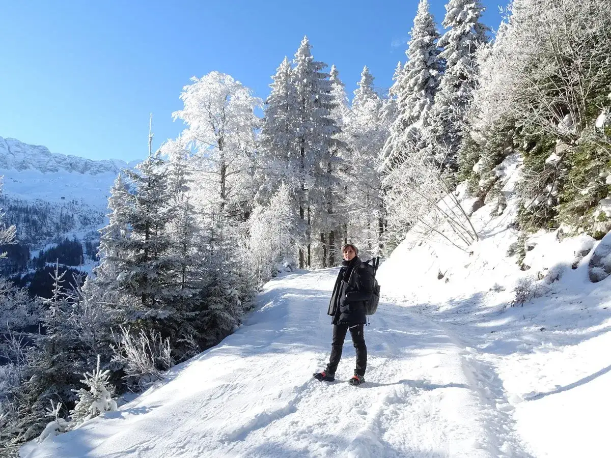Persona in piedi su un sentiero innevato, circondata da alberi coperti di brina, godendosi le attivit&agrave; invernali.