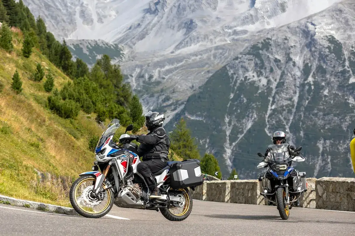 Due motociclisti affrontano una strada di montagna. Andare in moto fa bene, specialmente con panorami cos&igrave; mozzafiato!
