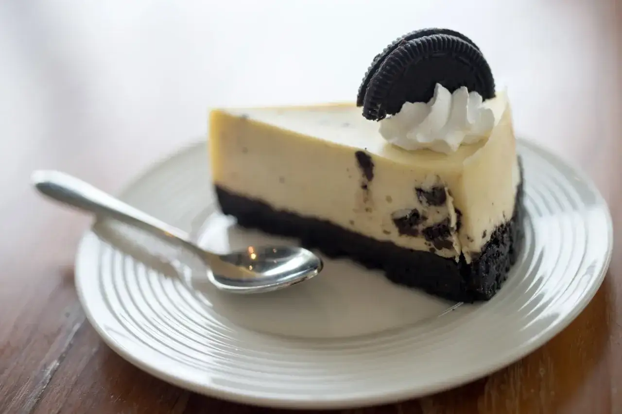 Pyszny sernik Oreo z kawałkami ciastek i bitą śmietaną na talerzu. Idealny na deser, gdy szukasz przepisu na coś wyjątkowego.