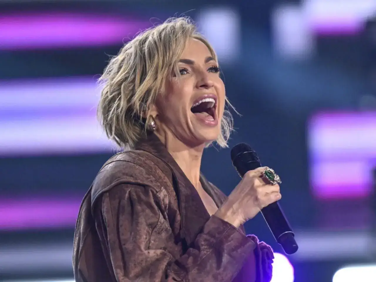 Anna Wyszkoni śpiewa na scenie, trzymając mikrofon. Jej emocjonalne wykonanie porusza publiczność.