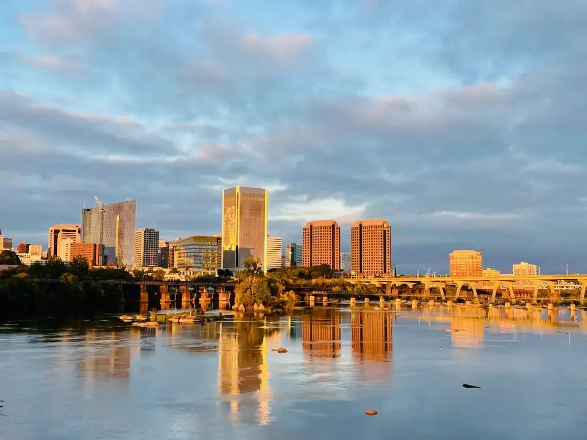 Sunrise over the James River reflects the Richmond skyline, hinting at the many fun things to do in Richmond, VA.