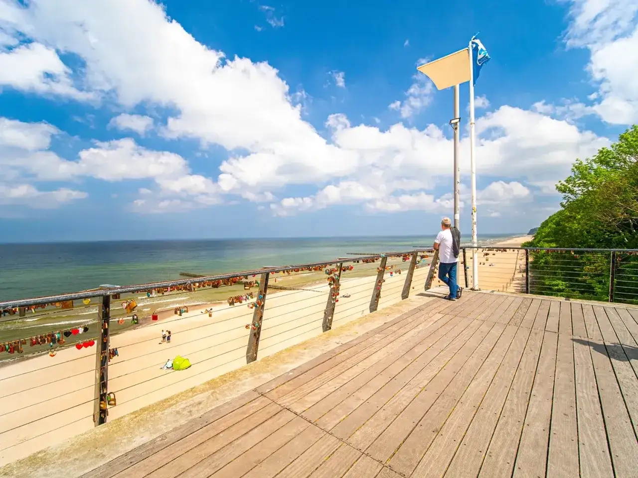 Widok na plażę i morze z molo w Rewalu. Miłośnicy odwiedzają rewal i okolice atrakcje, wieszając kłódki miłości na balustradzie.