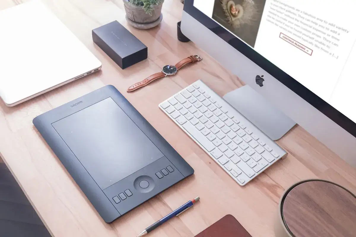Tablet graficzny Wacom, klawiatura, komputer i laptop na biurku. To narzędzie do cyfrowego rysowania i edycji grafiki.