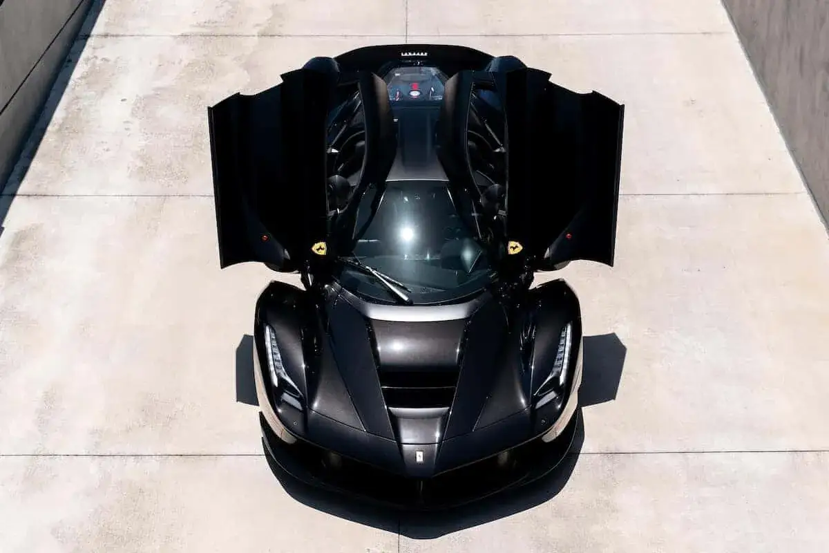 Czarny Ferrari LaFerrari z otwartymi drzwiami, prezentujący swój potężny silnik. Ikona motoryzacji.