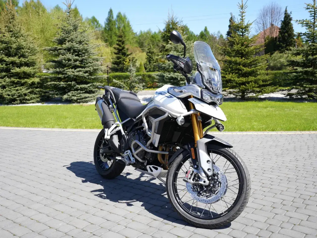 Biały motocykl Triumph Tiger 900 Rally Pro na podjeździe. Zapoznaj się z jego możliwościami, poznaj triumph tiger 900 dane techniczne.