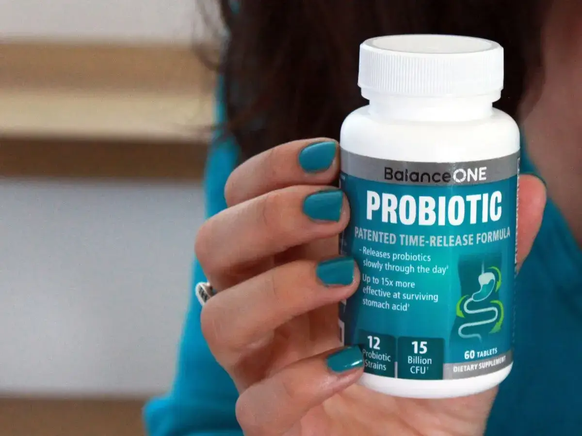 Mano con smalto turchese tiene flacone di BalanceONE Probiotic. Chiss&agrave; biotransit dopo quanto fa effetto?