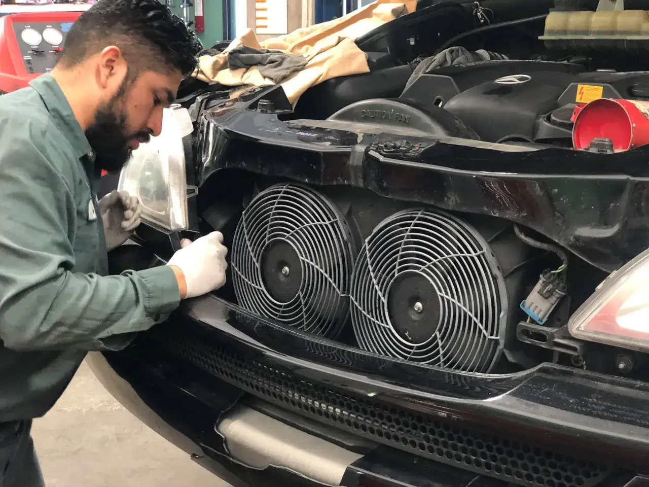 Mec&aacute;nico revisa el motor de un coche. El radiador hace ruido y necesita atenci&oacute;n.