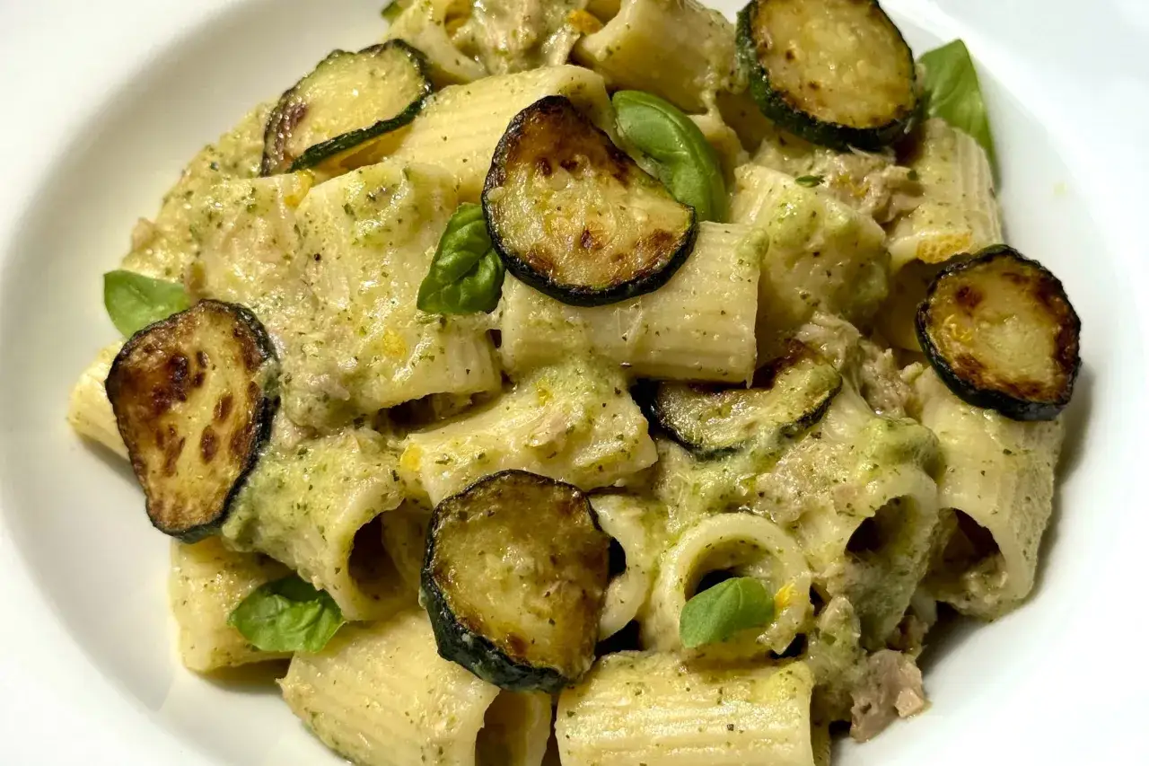 Pasta con zucchine e tonno, un piatto cremoso e saporito, guarnito con basilico fresco.