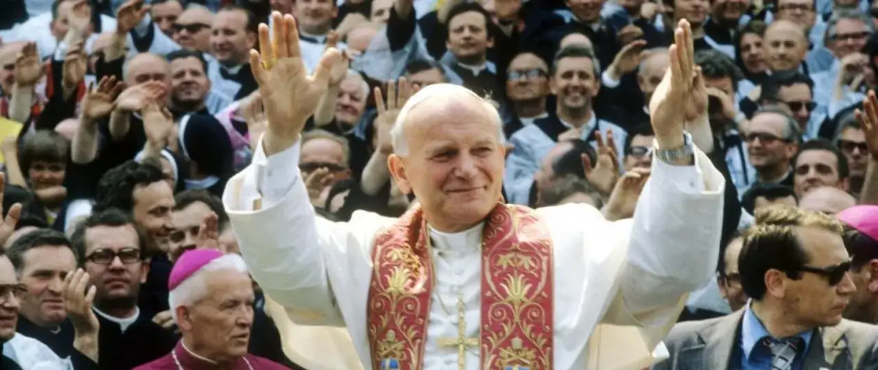 Jan Paweł II pozdrawia tłum. Wiele osób wznosi ręce, jakby uczestnicząc w codziennej modlitwie do św. Jana Pawła II.