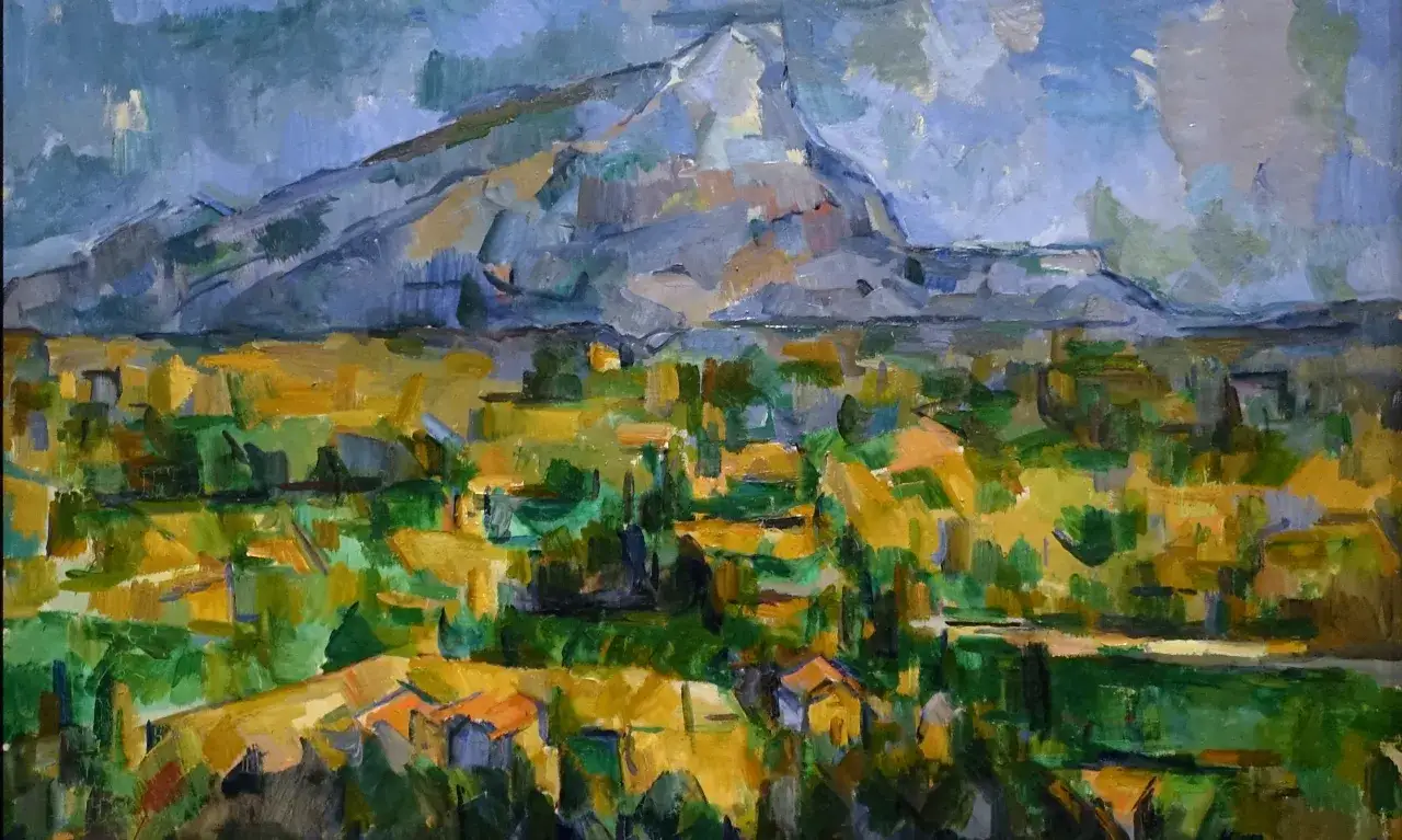 Góra Świętej Wiktorii na obrazie Paula Cézanne'a, zdominowana przez błękitne niebo i skaliste zbocza, otoczona bujną, zielono-żółtą roślinnością i domami.