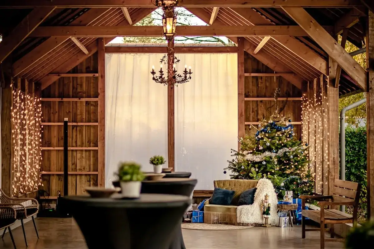 Une ambiance chaleureuse pour un mariage en hiver : sapin d&eacute;cor&eacute;, guirlandes lumineuses et mobilier cosy dans une grange en bois.