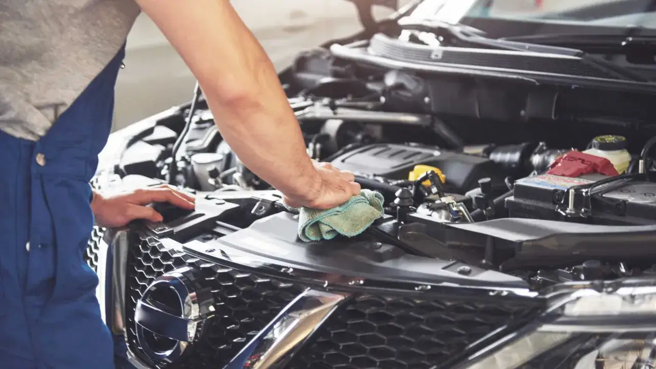 Mechanik w niebieskim kombinezonie czyści silnik, próbując zdiagnozować usterkę.