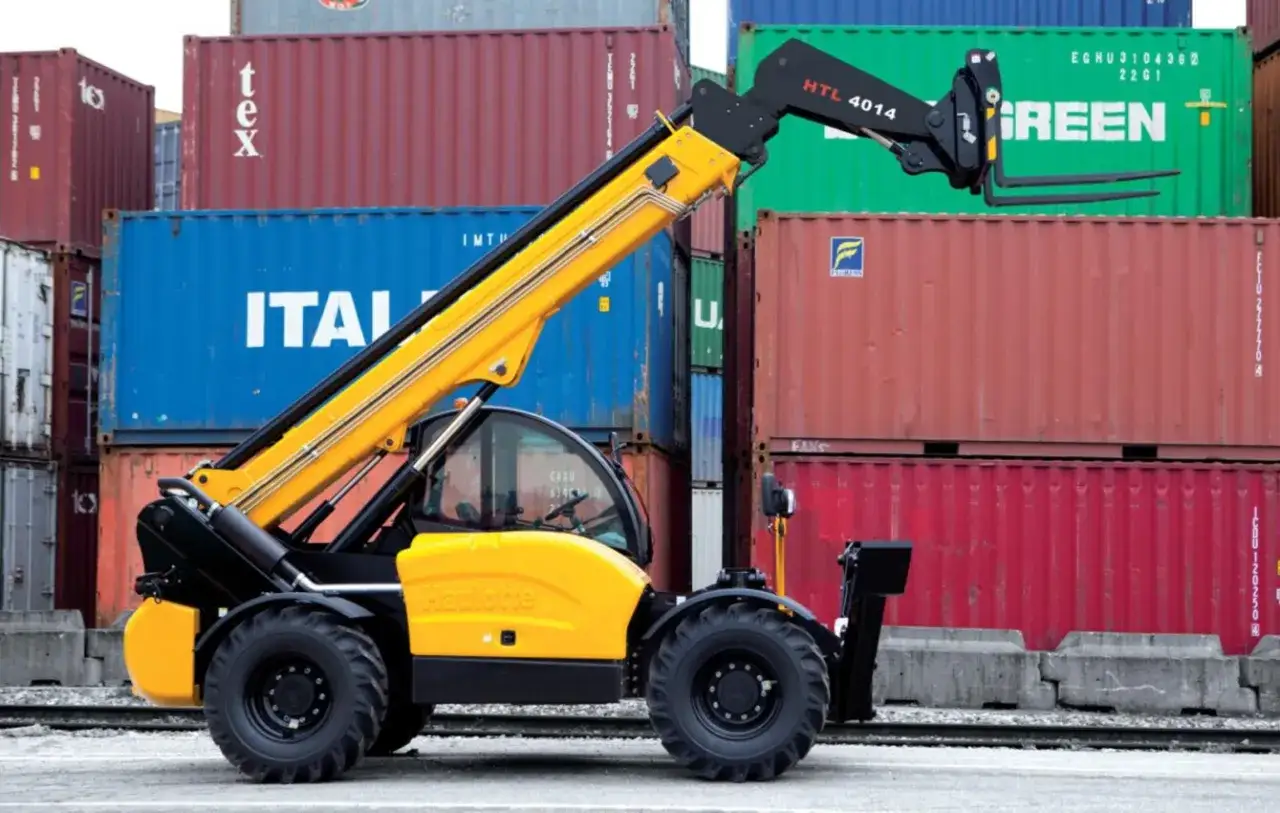 Żółty ładowarka teleskopowa z widłami, gotowa do pracy przy kontenerach. Posiadanie uprawnień na manitou to klucz do efektywnego transportu.