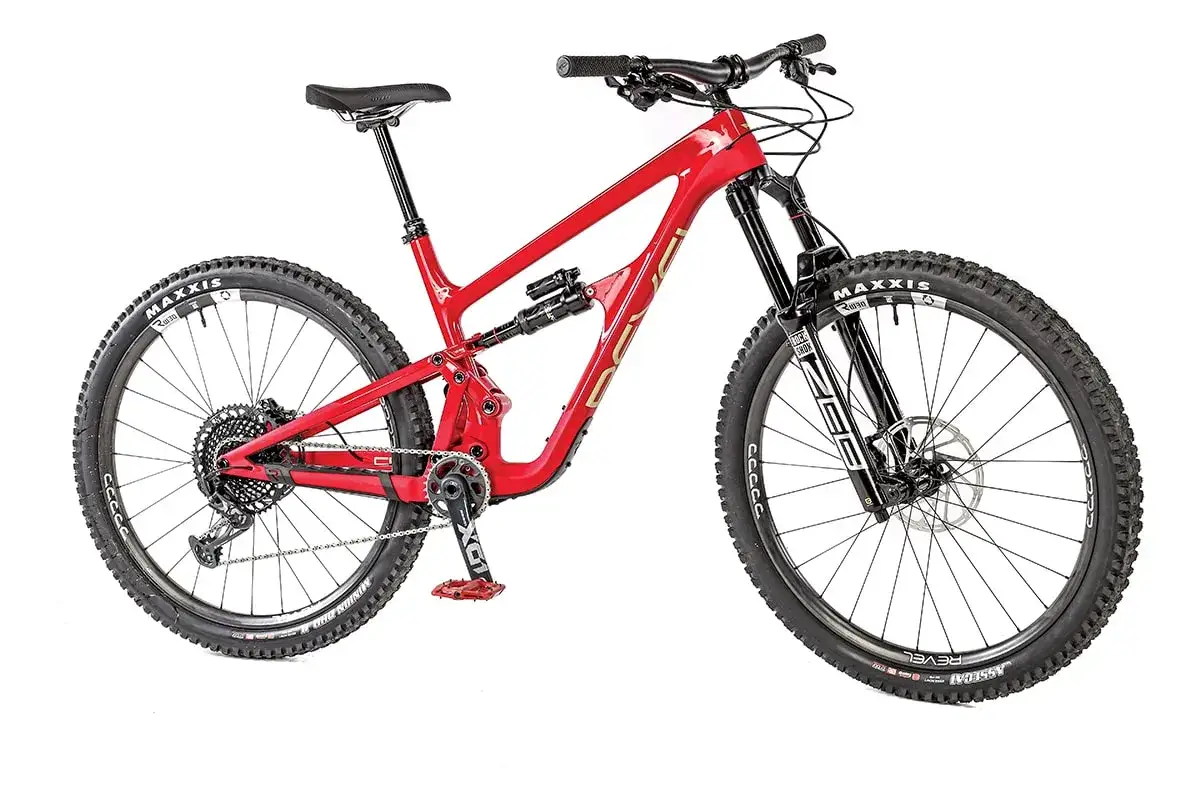 A bright red full-suspension mountain bike, a Revel Rail, ready to conquer any trail with its robust frame and knobby tires.