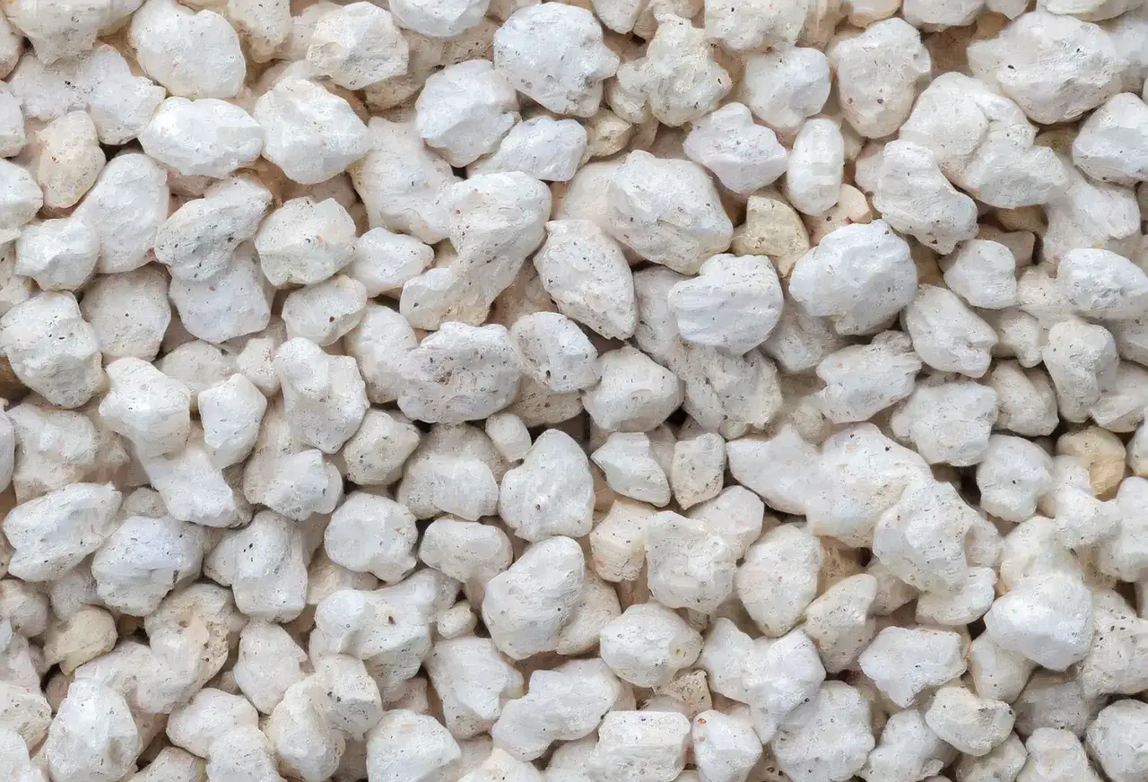 Gros plan sur une texture de perlite exfoliée, ces petits granulés blancs et poreux sont parfaits pour l'aération des sols.