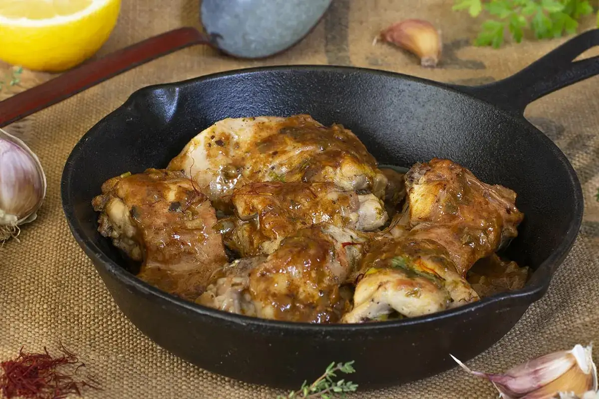Sabroso conejo al ajillo en sart&eacute;n de hierro fundido, con ingredientes frescos como lim&oacute;n, ajo y azafr&aacute;n.