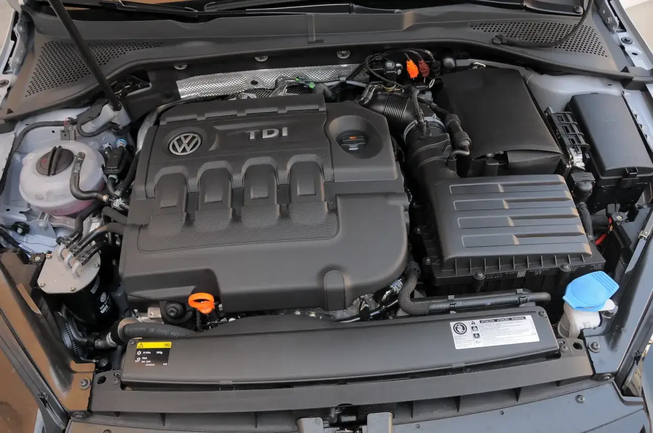 Motore 1.6 TDI Volkswagen, con coperchio nero e logo TDI ben visibile. Componenti del sistema di raffreddamento e aspirazione.