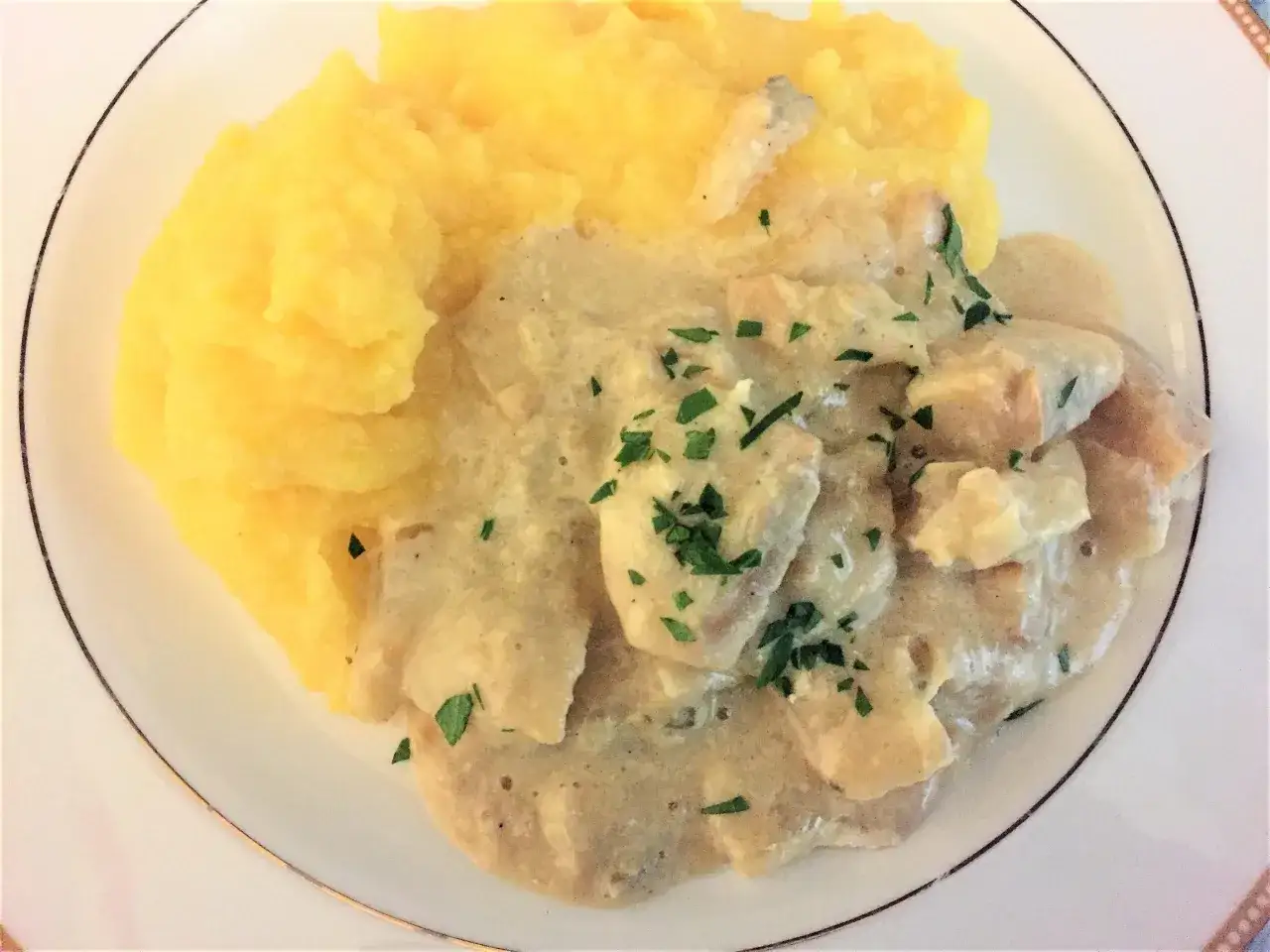 Piatto di baccal&agrave; alla vicentina cremoso, servito con polenta gialla e guarnito con prezzemolo tritato.