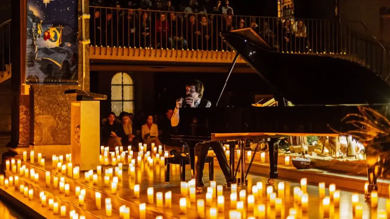 Un pianista canta en un concierto con velas. El escenario está iluminado por cientos de velas, creando una atmósfera mágica.
